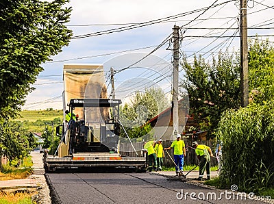 Targoviste, Romania - 2019. Workers operating asphalt paver machine during road construction on a sunny day. Construction of a new Editorial Stock Photo