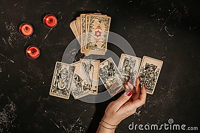 Tarot cards and female hands of fortune teller on black magic table Stock Photo