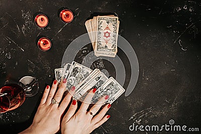 Tarot cards and female hands of fortune teller on black magic table Stock Photo