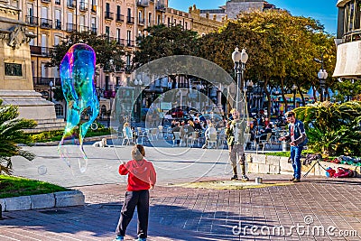 TARRAGONA, SPAIN, DECEMBER 29, 2015: a group of street performers is making soap bubbles in order to amuse people Editorial Stock Photo