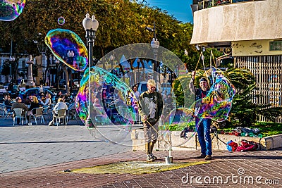 TARRAGONA, SPAIN, DECEMBER 29, 2015: a group of street performers is making soap bubbles in order to amuse people Editorial Stock Photo