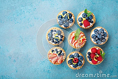 Tartlets or cake with cream cheese and berry on turquoise table from above. Delicious colorful pastry dessert. Stock Photo