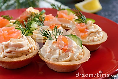 Tartlets with cream cheese and salted salmon on a red plate. Tasty light snack for a party. Finger Food. Stock Photo