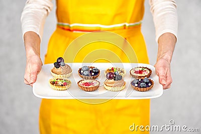 Tartlets on white plate in hand of woman in apron Stock Photo