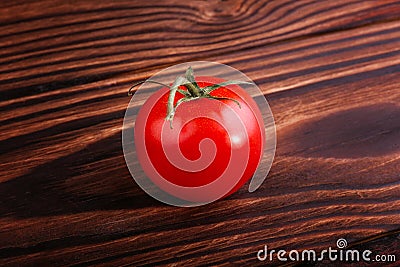 A tasteful red tomato on a brown background. Summer harvest. Natural organic vegetables full of nutrients. Healthy vegan diet. Stock Photo