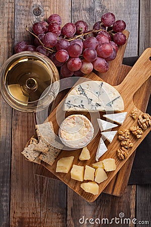 Tasting cheese dish on a wooden plate. Food for wine and romantic, cheese delicatessen on a wooden rustic table. Top view Stock Photo