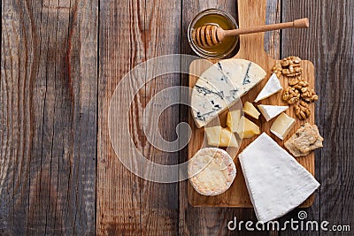 Tasting cheese dish on a wooden plate. Food for wine and romantic, cheese delicatessen on a wooden rustic table. Top view with cop Stock Photo