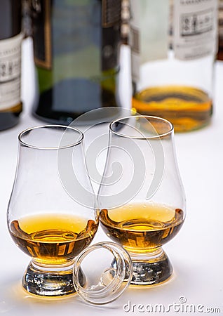 Tasting of whiskey, tulip-shaped tasting glasses with dram of Scotch single malt or blended whisky on white table Stock Photo