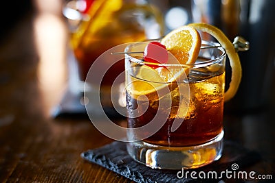 Tasty alcoholic old fashioned cocktail with orange slice, cherry, and lemon peel garnish Stock Photo