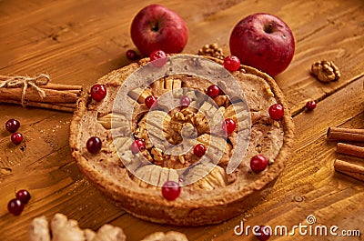 Tasty apple pie with fresh red cranberries and walnuts decorated with two apples, ginger and cinnamon. Just backed apple pie Stock Photo