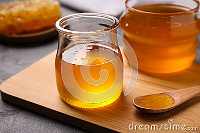 Tasty aromatic honey and wooden board on grey table Stock Photo