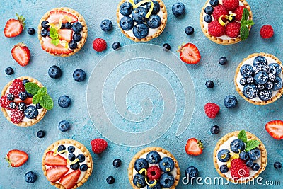Tasty berry tartlets or cake with cream cheese and different berries around. Pastry dessert top view. Stock Photo