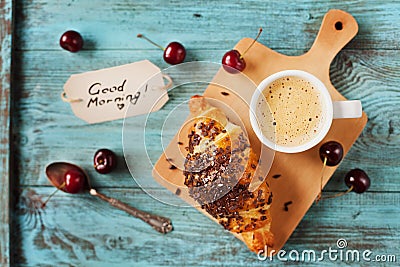 Tasty breakfast with fresh croissant, coffee, cherries and notes on a wooden table Stock Photo