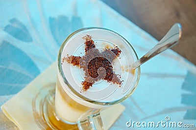 A tasty cappuccino drink in a large glass on the table. A chocolate star is on top of a cappuccino Stock Photo