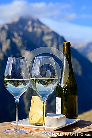 Tasty cheese and wine from Savoy region in France, tomme and reblochon de savoie cheeses and glass of white wine served outdoor Stock Photo