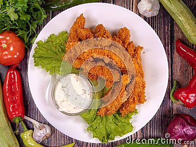 Tasty chicken bites with cornflakes in a plate, on a wooden table. Stock Photo