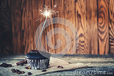 Tasty chocolate cupcake with sparkler on wooden background. Happy birthday concept. Delicious chocolate cupcake Stock Photo