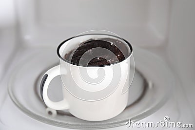 Tasty chocolate mug pie inside microwave. Cooking cake Stock Photo