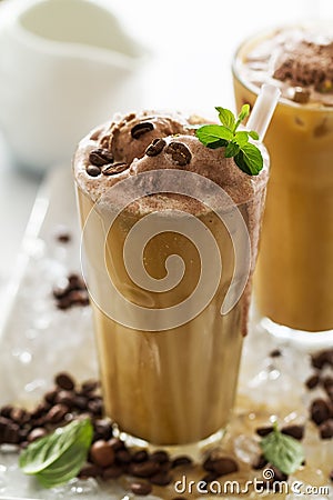 Tasty cold refreshing drink with coffee, milk, chocolate ice cream and ice in glass on ice background. Closeup. Stock Photo