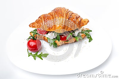 Tasty croissant with tomato and ruccola on the whie plate Stock Photo