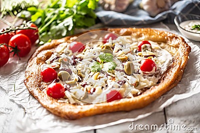Tasty and crusty langos perfectly served with whole cherry tomatoes, gratted cheese, beans and green greek olives Stock Photo