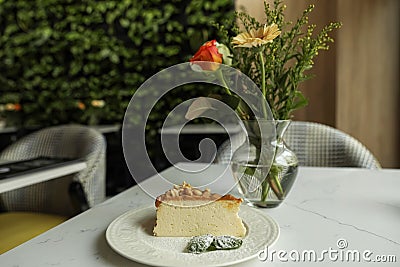 Tasty dessert and vase with flowers on white table in cafeteria Stock Photo