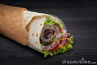 Tasty doner kebabs with fresh salad trimmings and shaved roasted meat served in tortilla wraps on brown paper as a Stock Photo