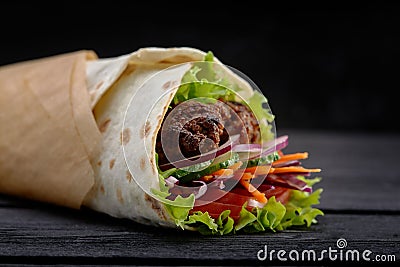 Tasty doner kebabs with fresh salad trimmings and shaved roasted meat served in tortilla wraps on brown paper as a Stock Photo