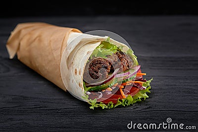 Tasty doner kebabs with fresh salad trimmings and shaved roasted meat served in tortilla wraps on brown paper as a Stock Photo