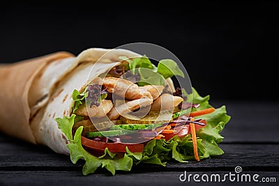 Tasty doner kebabs with fresh salad trimmings and shaved roasted meat served in tortilla wraps on brown paper as a Stock Photo