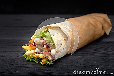 Tasty doner kebabs with fresh salad trimmings and shaved roasted meat served in tortilla wraps on brown paper as a Stock Photo