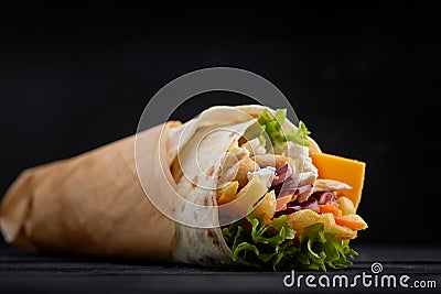 Tasty doner kebabs with fresh salad trimmings and shaved roasted meat served in tortilla wraps on brown paper as a Stock Photo
