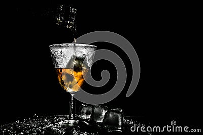 Tasty drink pouring in beautiful misted vintage glass with pieces of ice Stock Photo