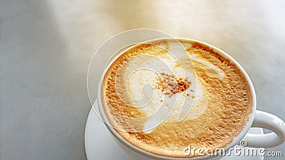 Tasty drinking, a cup of cappuccino coffee decorated with fluffy white and brown milk froth in white ceramic cup on gray table Stock Photo