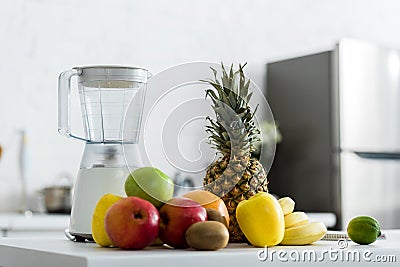 Tasty fruits near blender in kitchen Stock Photo