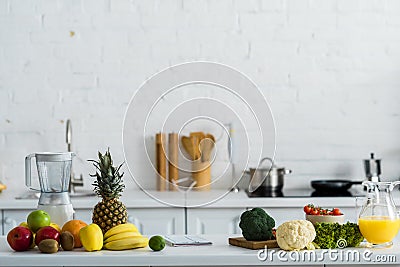 Tasty fruits and vegetables near blender and jug with orange juice Stock Photo