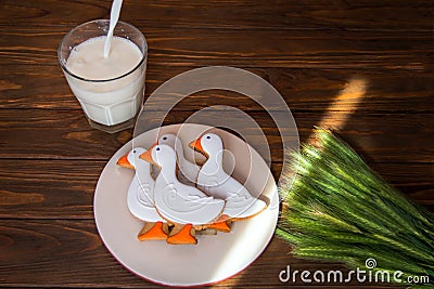 Tasty gingerbread suck shaped cookies on a plate with glass of milk and with ear of wheat on a wooden background Stock Photo