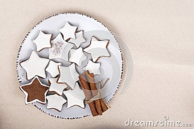 Tasty glazed painted cookies stars and cinnamon sticks on top view plate. Gingerbread Stock Photo