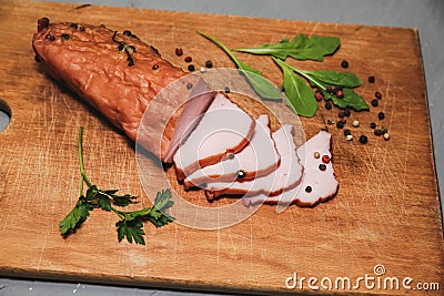 Tasty ham lying on the wooden panel plank. Meat with green leaves spinach. Food photo with pepper spices Stock Photo