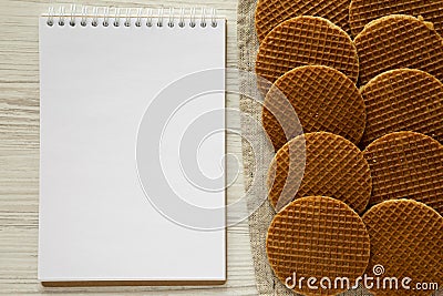 Tasty homemade dutch stroopwafels with honey-caramel filling, blank notepad on a white wooden background, top view. Flat lay, Stock Photo