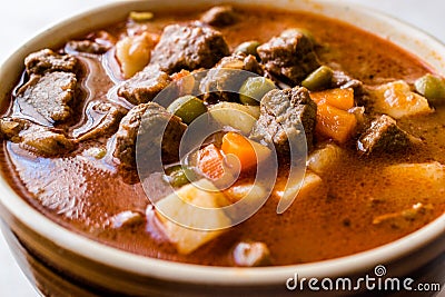 Tasty Hungarian Hot Goulash Soup Bograch or Gulas Lamb Meat Stew with Whole Grain Bread on Wooden Surface at Restaurant. Stock Photo