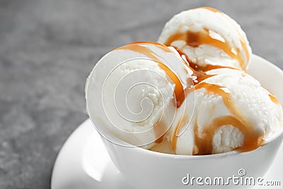 Tasty ice cream with caramel sauce in mug on table Stock Photo