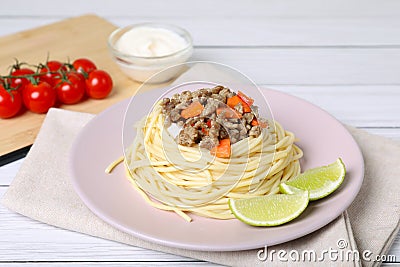Tasty minced meat with spaghetti, vegetables and lime on white wooden table, closeup Stock Photo