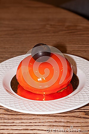 tasty orange cake with chocolate ball on white plate on wooden table Stock Photo