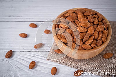 Tasty organic peeled almond snack in wooden bowl on white wooden background with copy space.Close up heap almonds shelled nut . Stock Photo