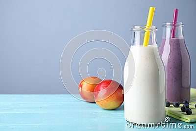 Tasty peach and blueberry milk shakes in bottles on light blue wooden table Stock Photo