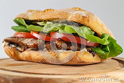 Tasty pork steak sandwich in a ciabatta with tomatos, lettuce Stock Photo