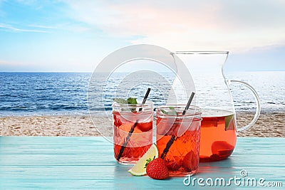 Tasty refreshing drink on table against sandy beach Stock Photo