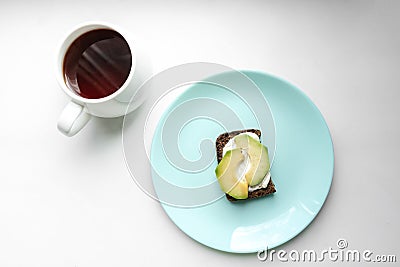 Tasty sandwich with avocado on a turquoise plate and a cup of tea on a white background Stock Photo