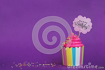 Tasty strawberry cupcake with sprinkles and Happy Birthday banner on violet background. Party background Stock Photo